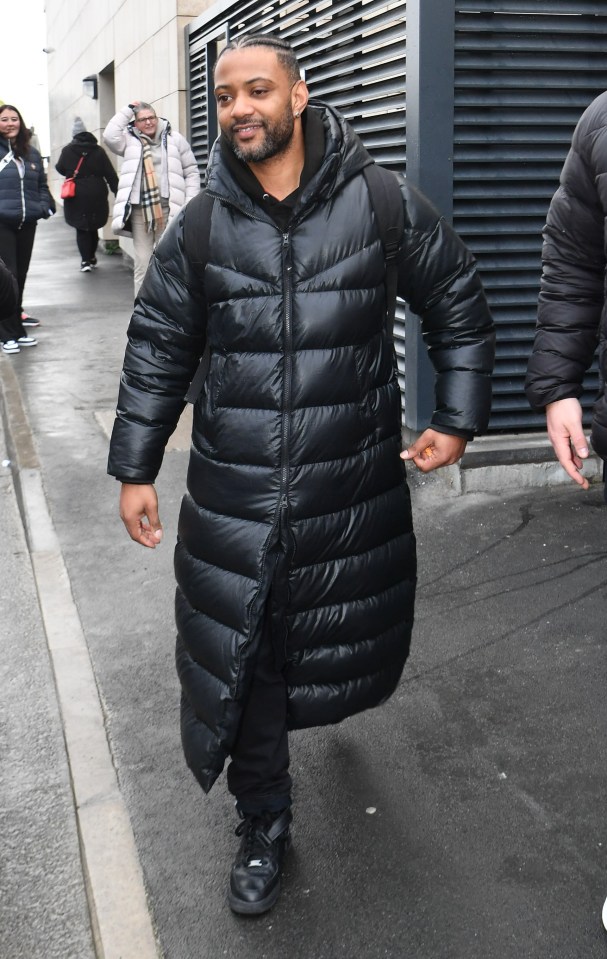 a man in a long black coat is walking down the street