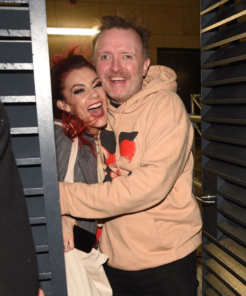 a man in a tan hoodie is hugging a woman with red hair