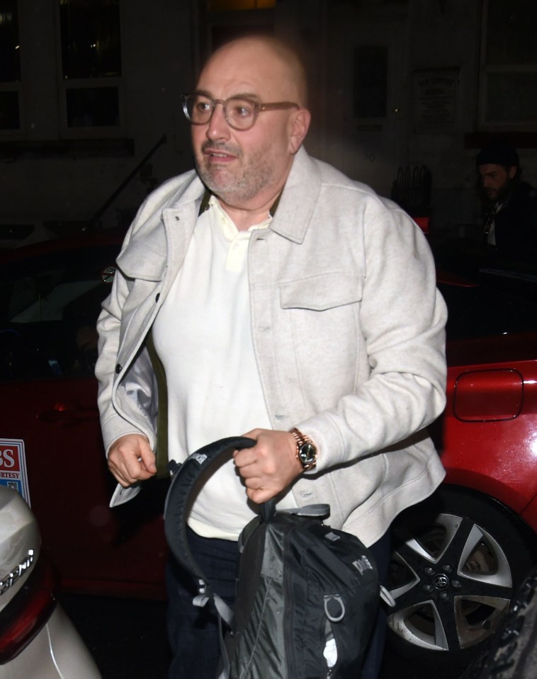 a man carrying a bag in front of a red car with a sign that says ' s ' on it