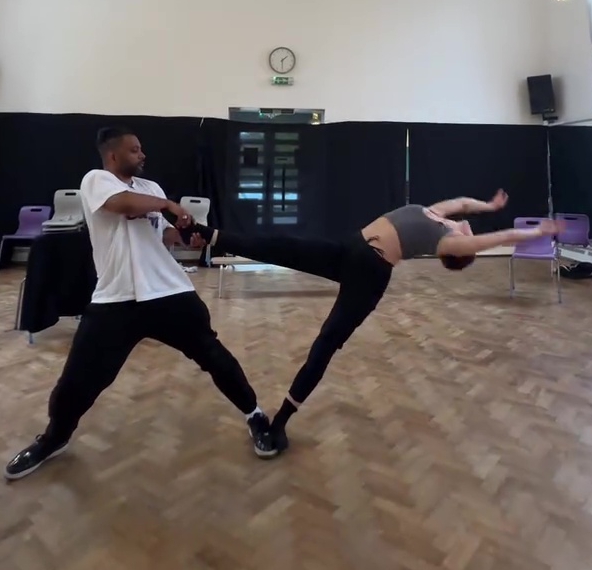 a man and a woman are dancing in a room with a clock on the wall