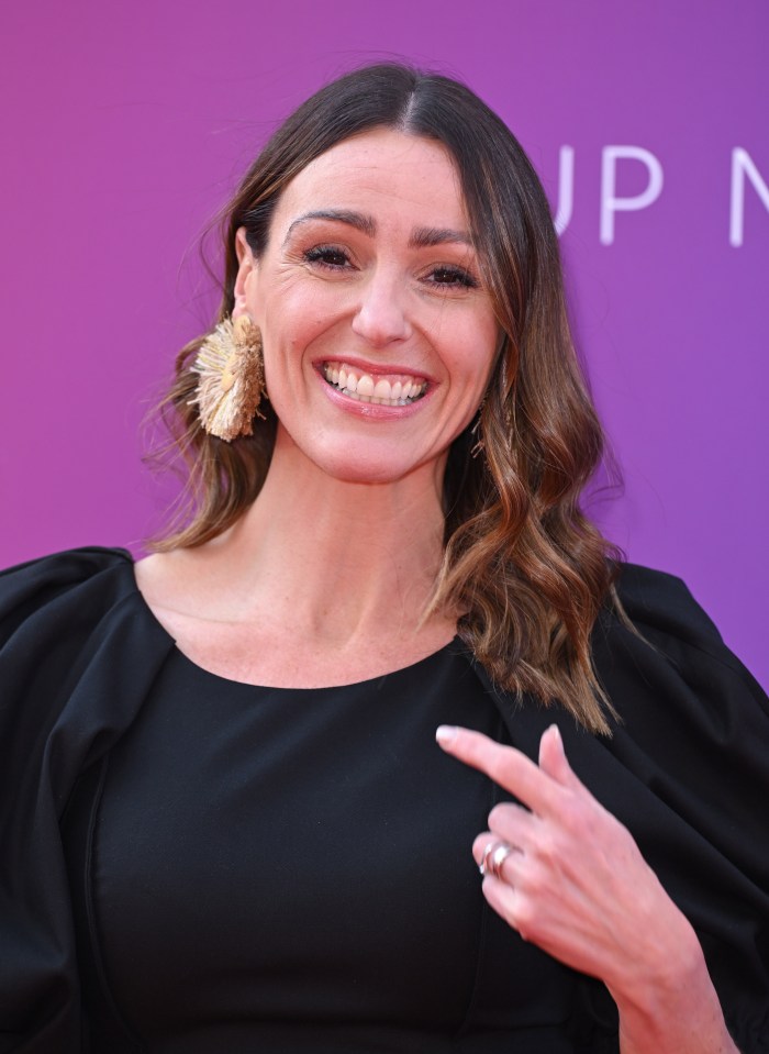 a woman in a black dress is smiling and pointing at something