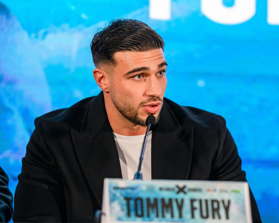 tommy fury is speaking into a microphone at a press conference