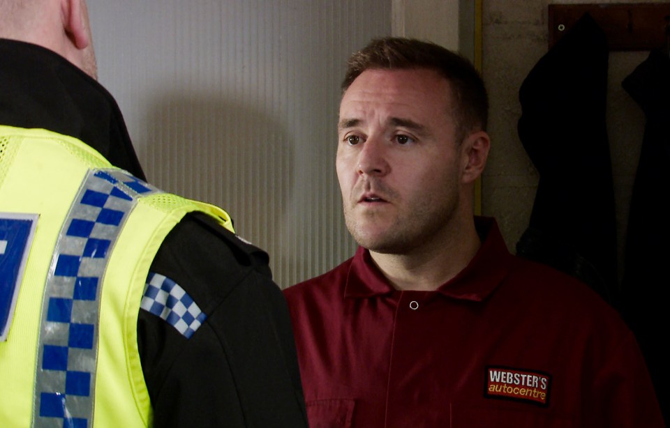 a man wearing a webster 's autocentre shirt talks to another man