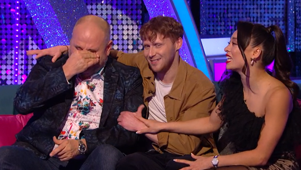 two men and a woman are sitting on a couch laughing