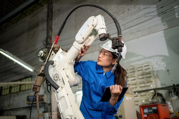 a woman is working on a robotic arm while holding a clipboard