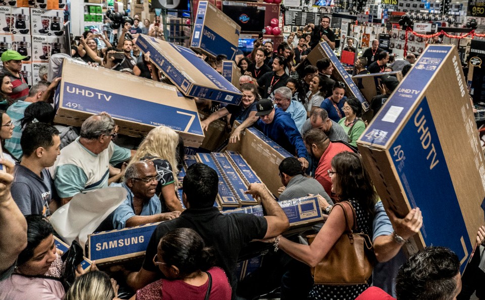 a crowd of people holding up samsung uhd tv boxes