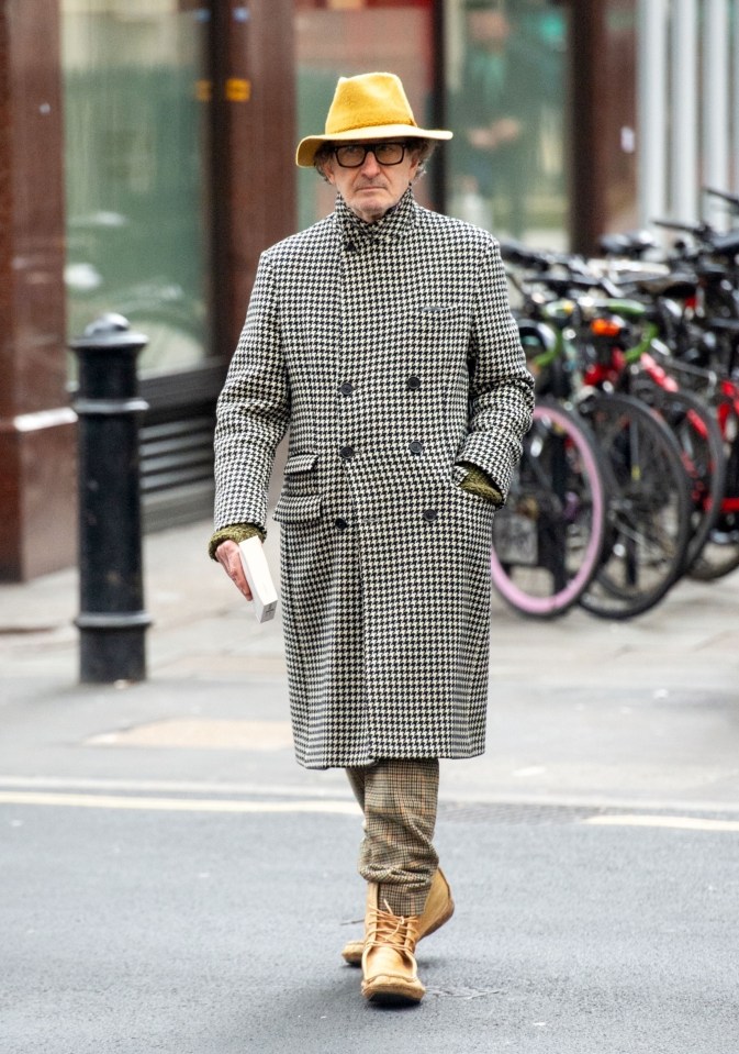 a man wearing a yellow hat and glasses is walking down the street