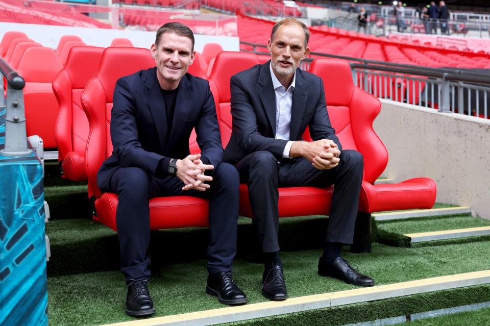 two men in suits sit on a red bench in a stadium