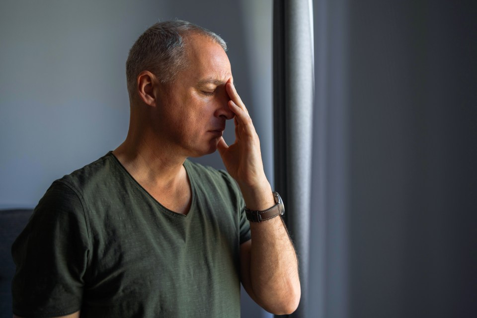 a man in a green shirt has his hand on his forehead