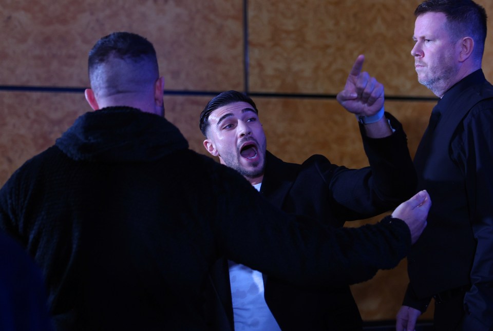 a man in a black jacket is pointing at another man in a white shirt