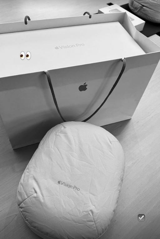 an apple vision pro box sits next to a white pillow