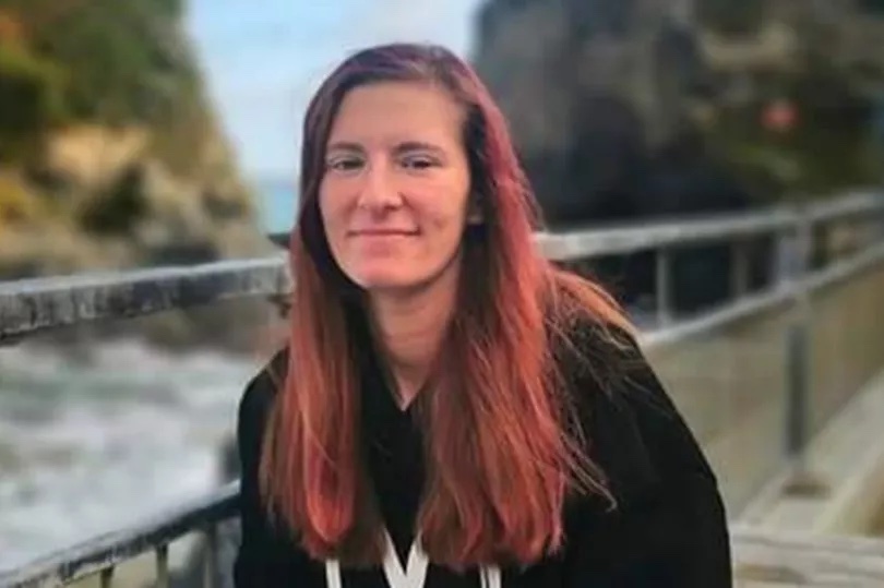 a woman with red hair is sitting on a railing looking at the camera .