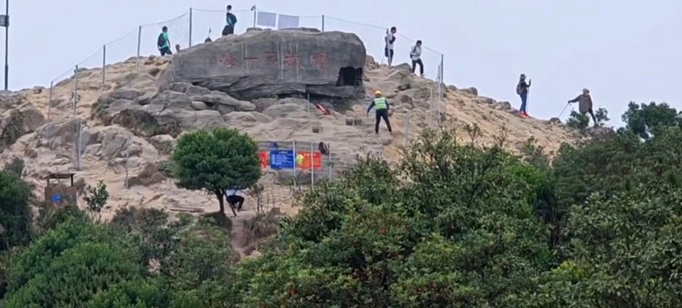 a group of people standing on top of a rocky hill with chinese writing on it