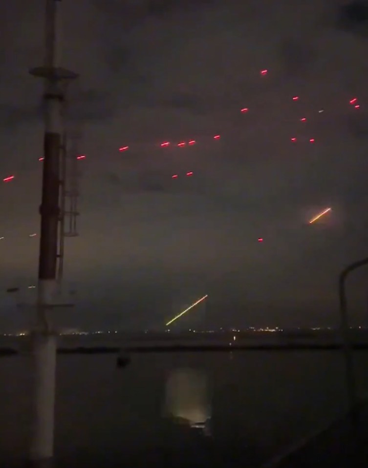 a bunch of red lights are flying in the night sky