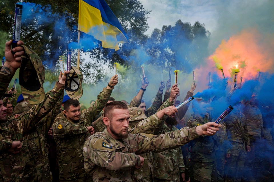 a group of soldiers are holding blue and orange smoke flares and flags