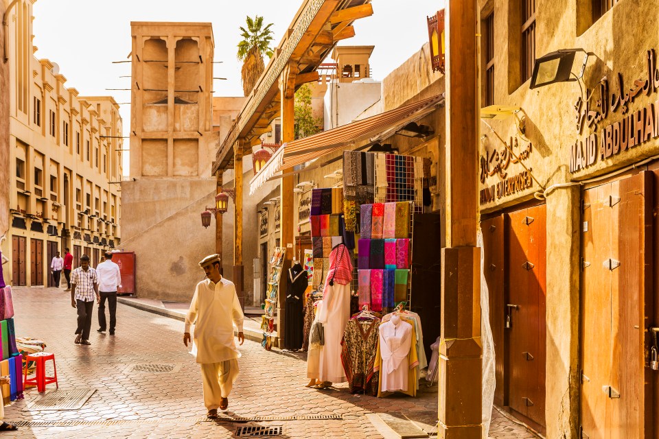 a man walks down a narrow street in front of a store called land agriculture