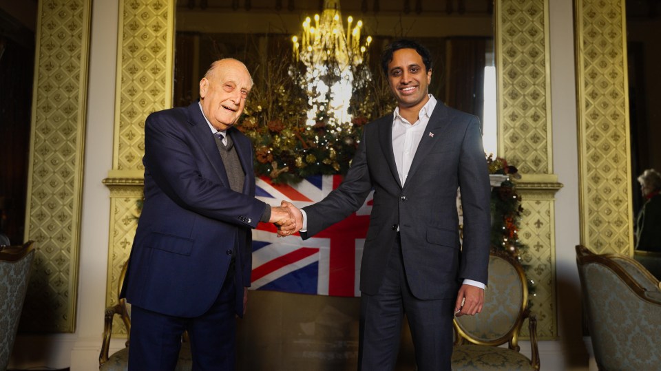 two men shaking hands in front of a british flag