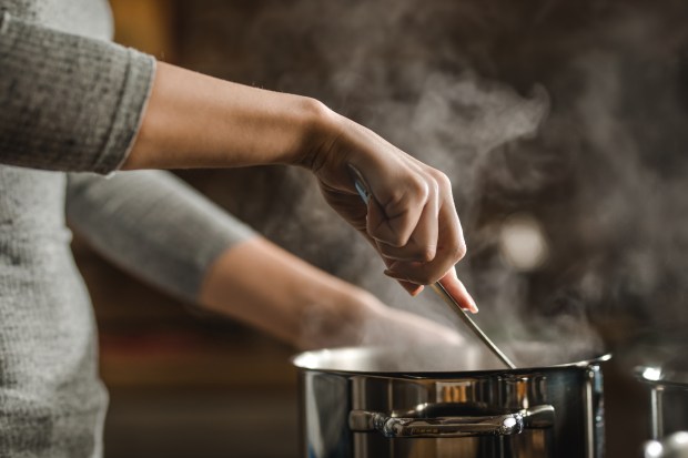 a woman stirs a pot of boiling water with a spoon