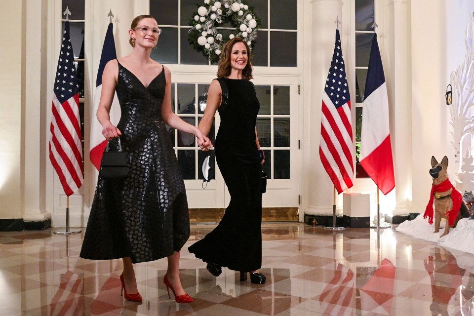 a woman in a black dress holds the hand of another woman