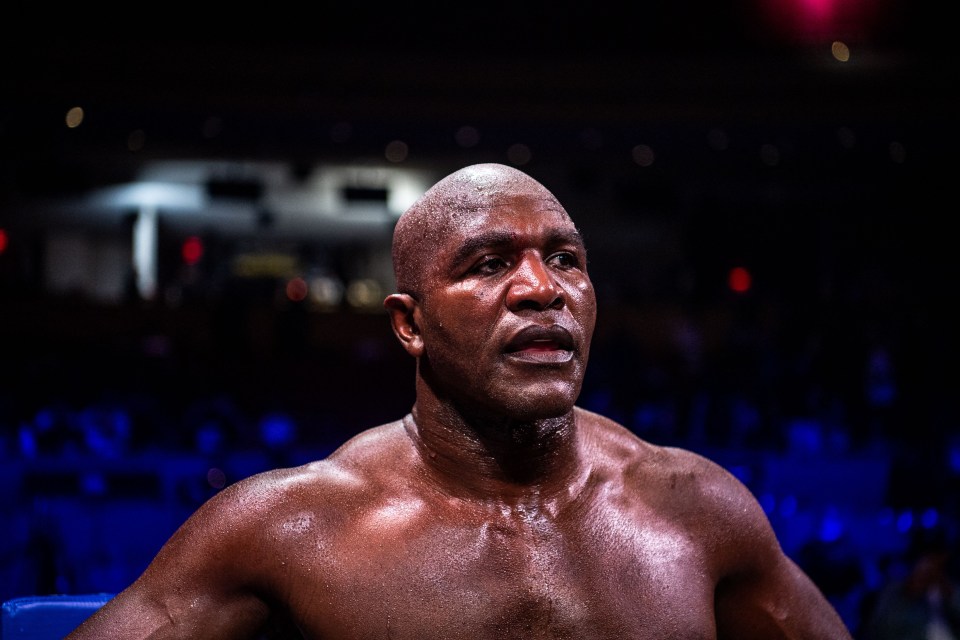 a shirtless boxer stands in a ring with a blue padding