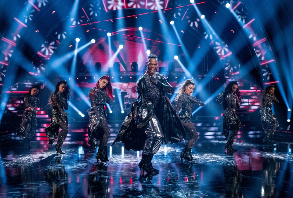 a group of dancers perform on a stage with blue lights