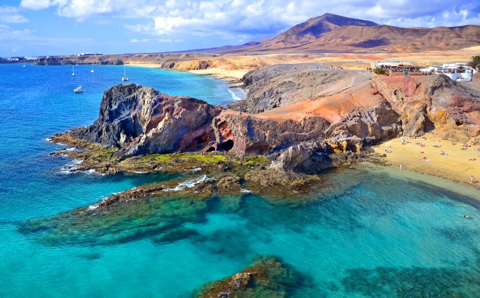 a beach with boats in the water and mountains in the background