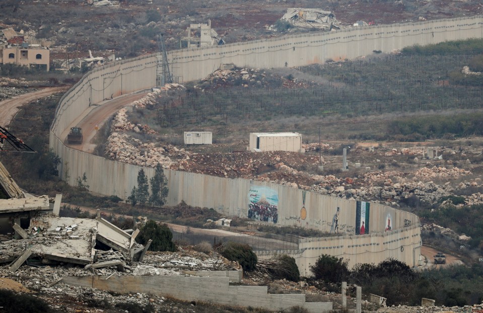 Destroyed buildings and mounts of rubble can be seen near the border wall between Lebanon and Israel