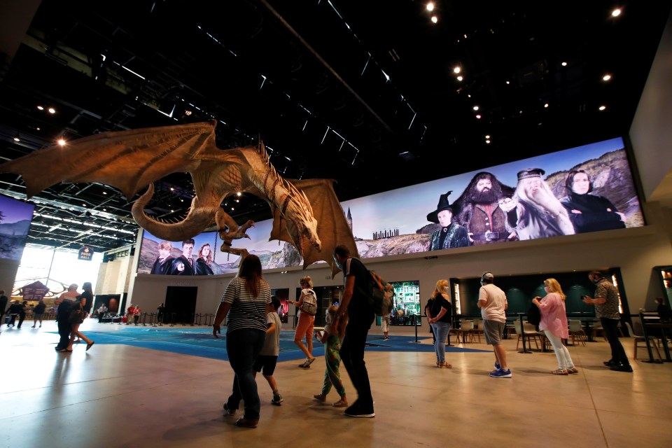 a group of people standing in front of a large screen with harry potter characters on it