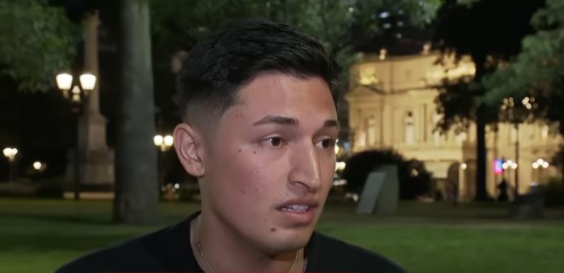 a young man is standing in a park at night talking to a camera .