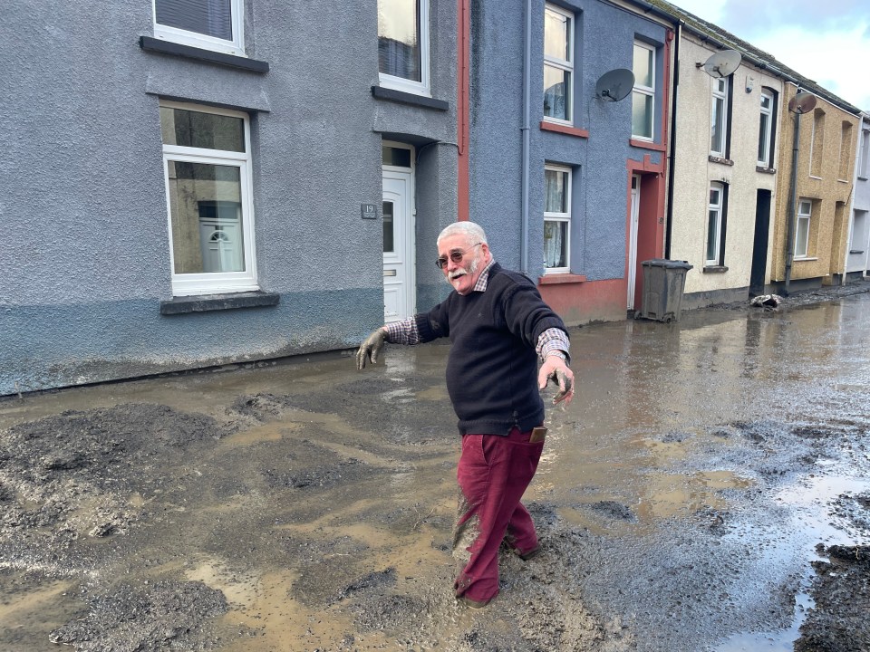 A man walking through flood water after the mud slide in Wales