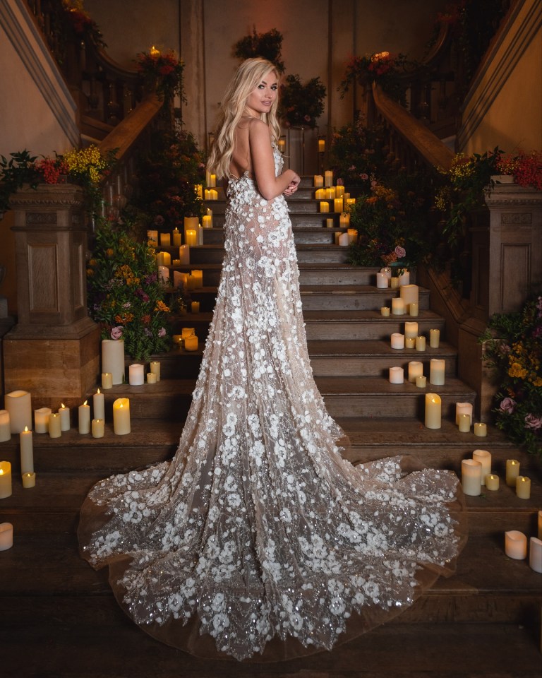 a woman in a wedding dress stands on a set of stairs surrounded by candles and flowers