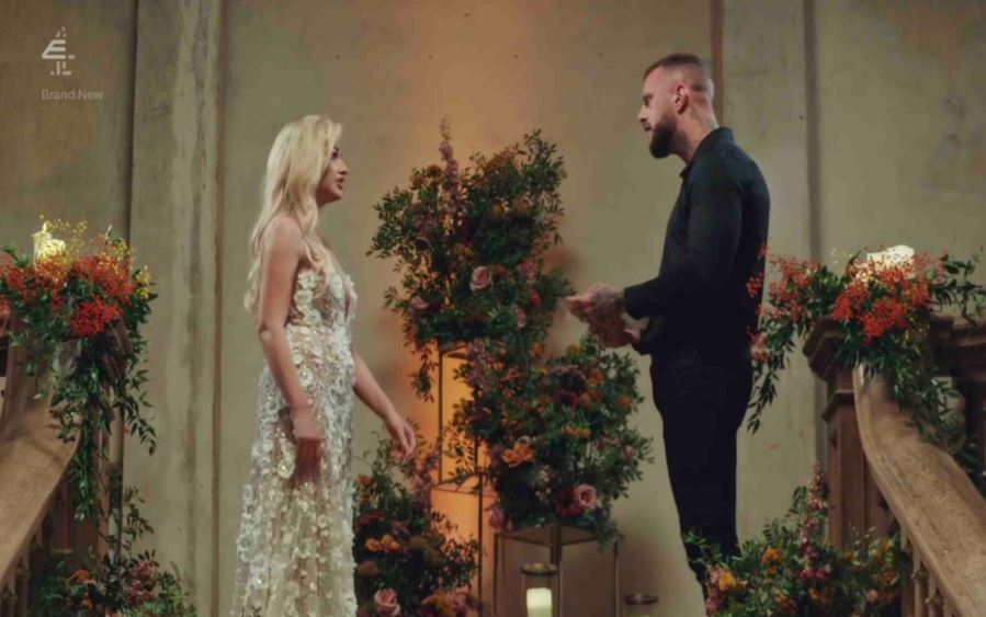 a man and a woman are standing next to each other in front of flowers and a bbc logo