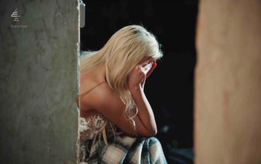 a blonde woman covering her face with her hands in front of a sign that says brand new