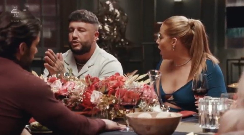 a group of people are sitting around a table with flowers and wine glasses .