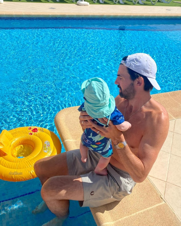 a man is holding a baby in front of a swimming pool