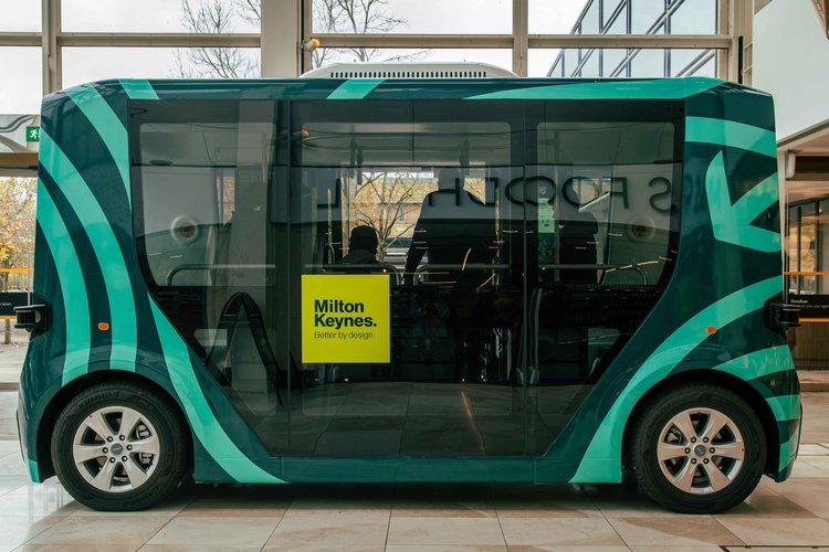 a green vehicle with a yellow sign that says milton keynes