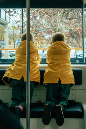 two young boys are sitting on a bus looking out the window .