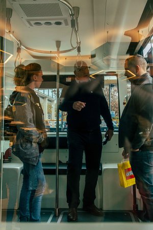 a group of people are standing on a bus talking to each other .