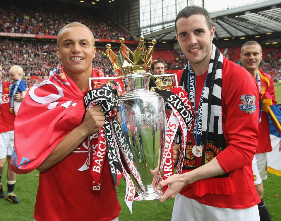 two soccer players holding a trophy that says barclays on it