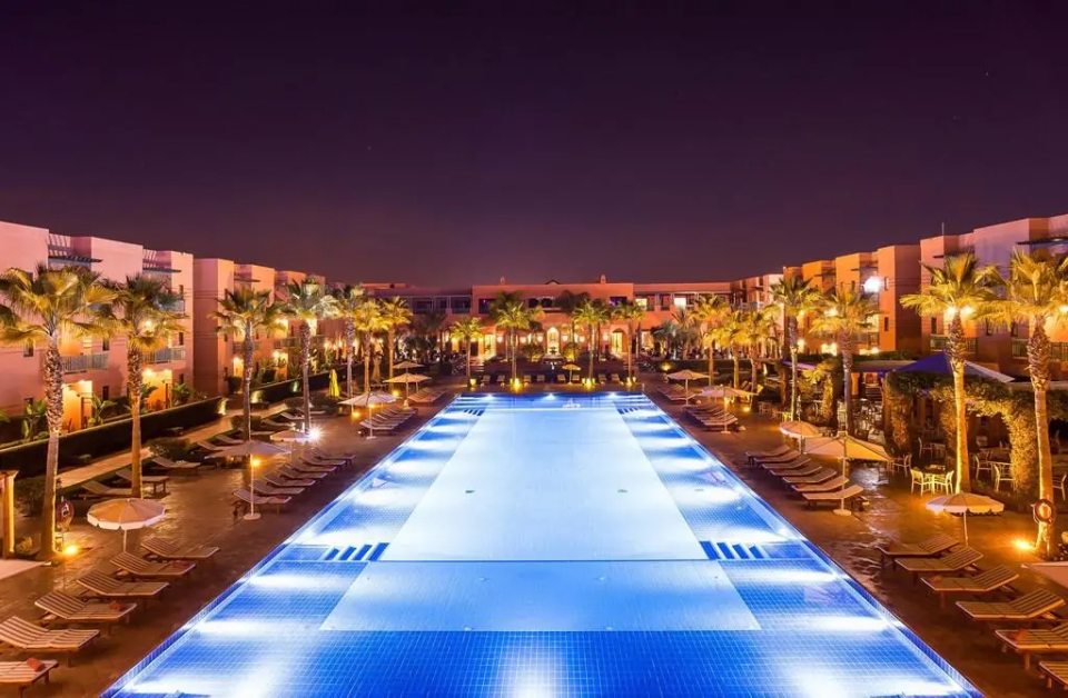 a large swimming pool is lit up at night