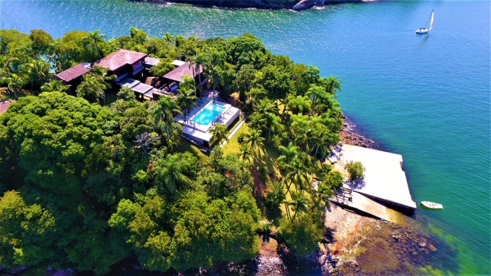 a large house sits on a small island in the middle of a body of water