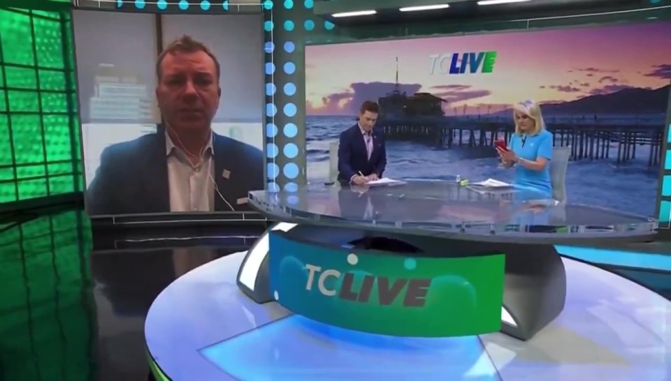 a man and a woman are sitting at a table in front of a sign that says tclive