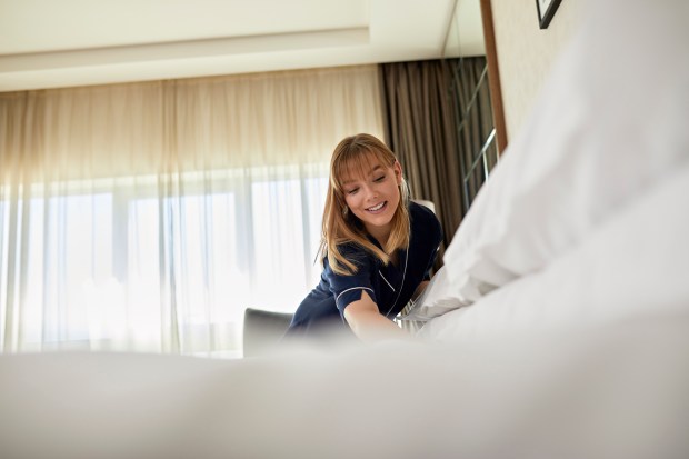 a woman is making a bed in a hotel room