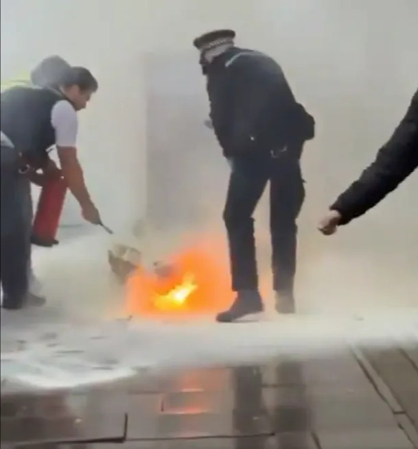 A police officer uses a smaller extinguisher to put out the flames