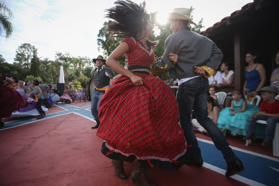 People in traditional outfits dance at the Festa Confederada