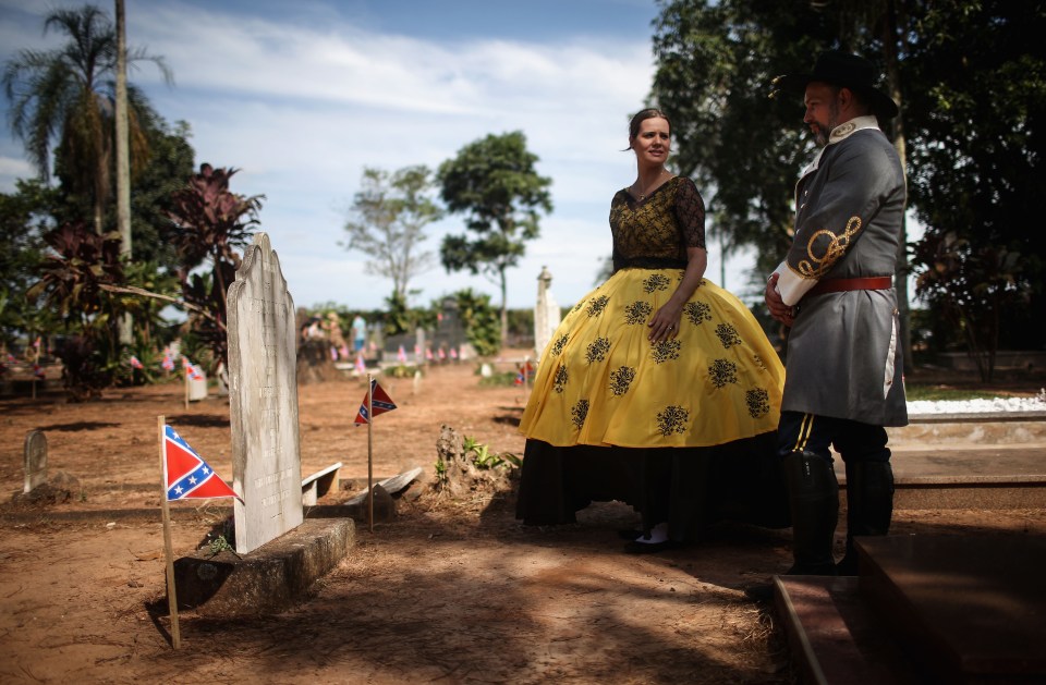 Fred Padovese (R), Brazilian descendant of American settlers, and Livia Paulillo visit a settlers grave dressed in traditional garb