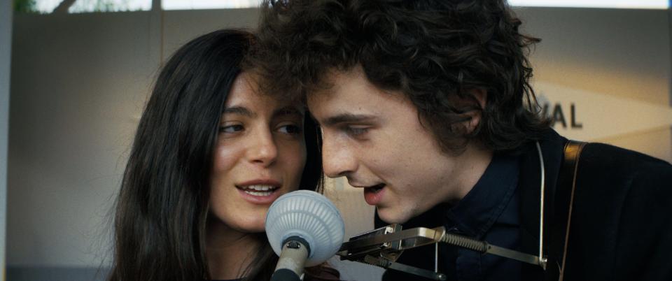 Timothee Chalamet as Bob Dylan and Monica Barbaro as Joan Baez singing together.