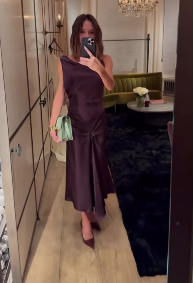 Woman in a purple dress and light green purse taking a selfie.