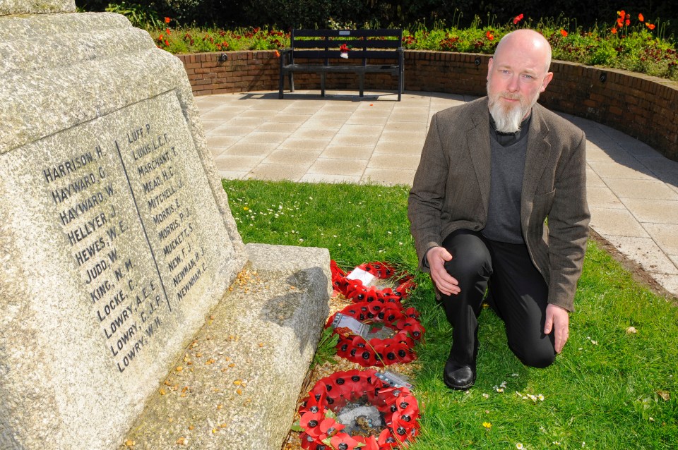 Vicar kneeling by war memorial.