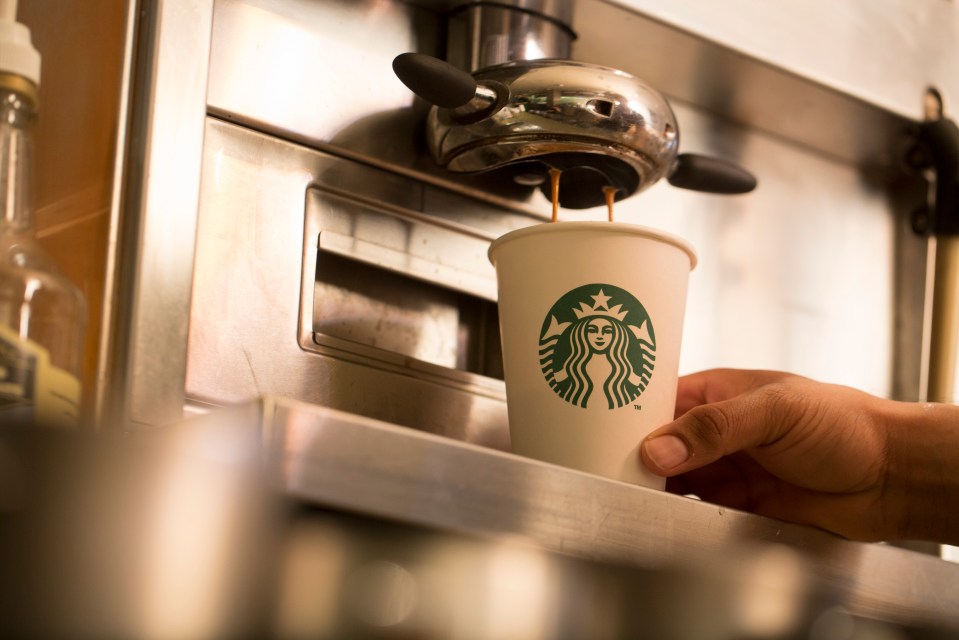 Coffee being poured into a Starbucks cup.